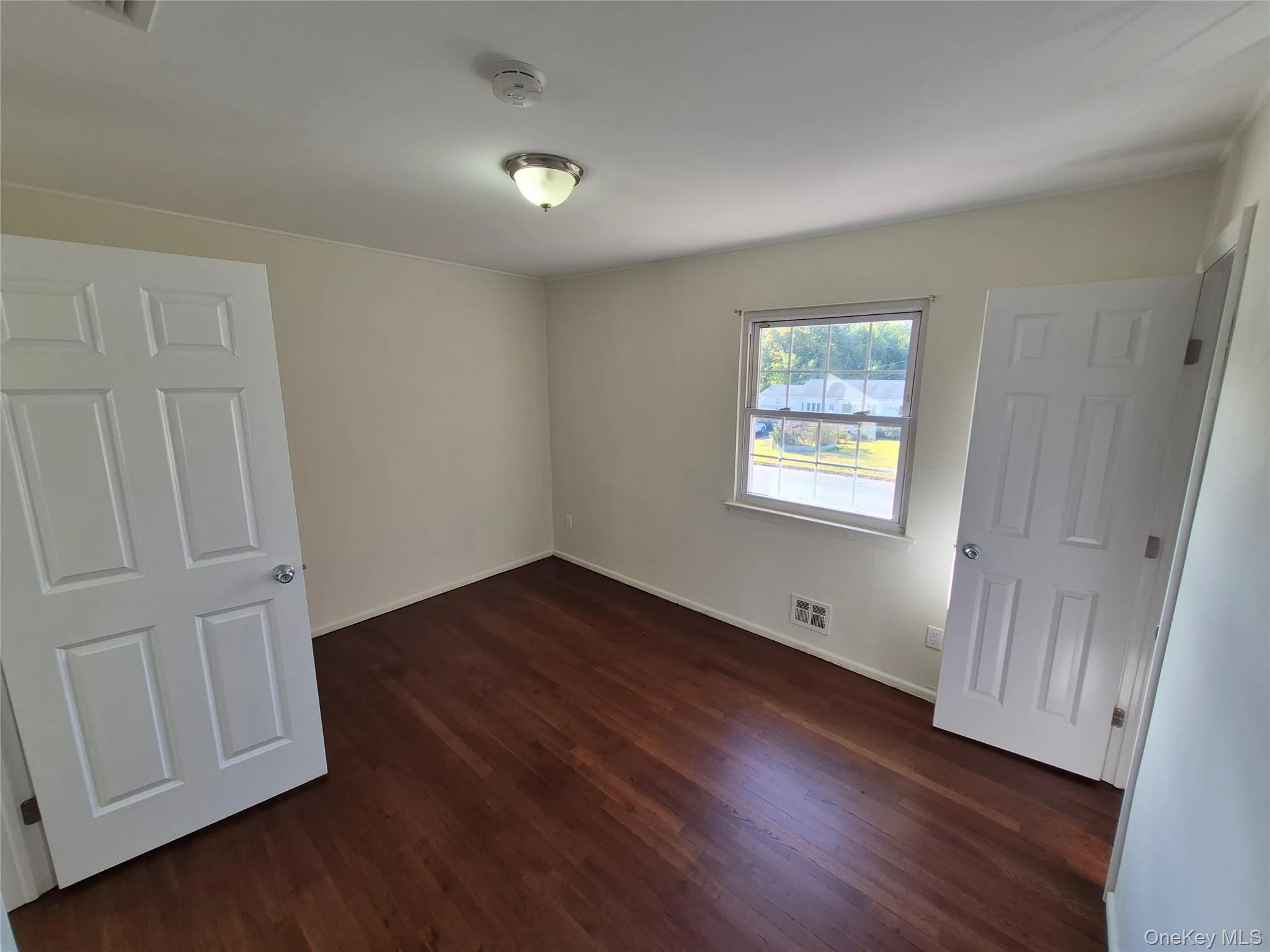 Unfurnished bedroom with dark wood-style floors and baseboards Unfurnished bedroom with dark wood-style floors and baseboards