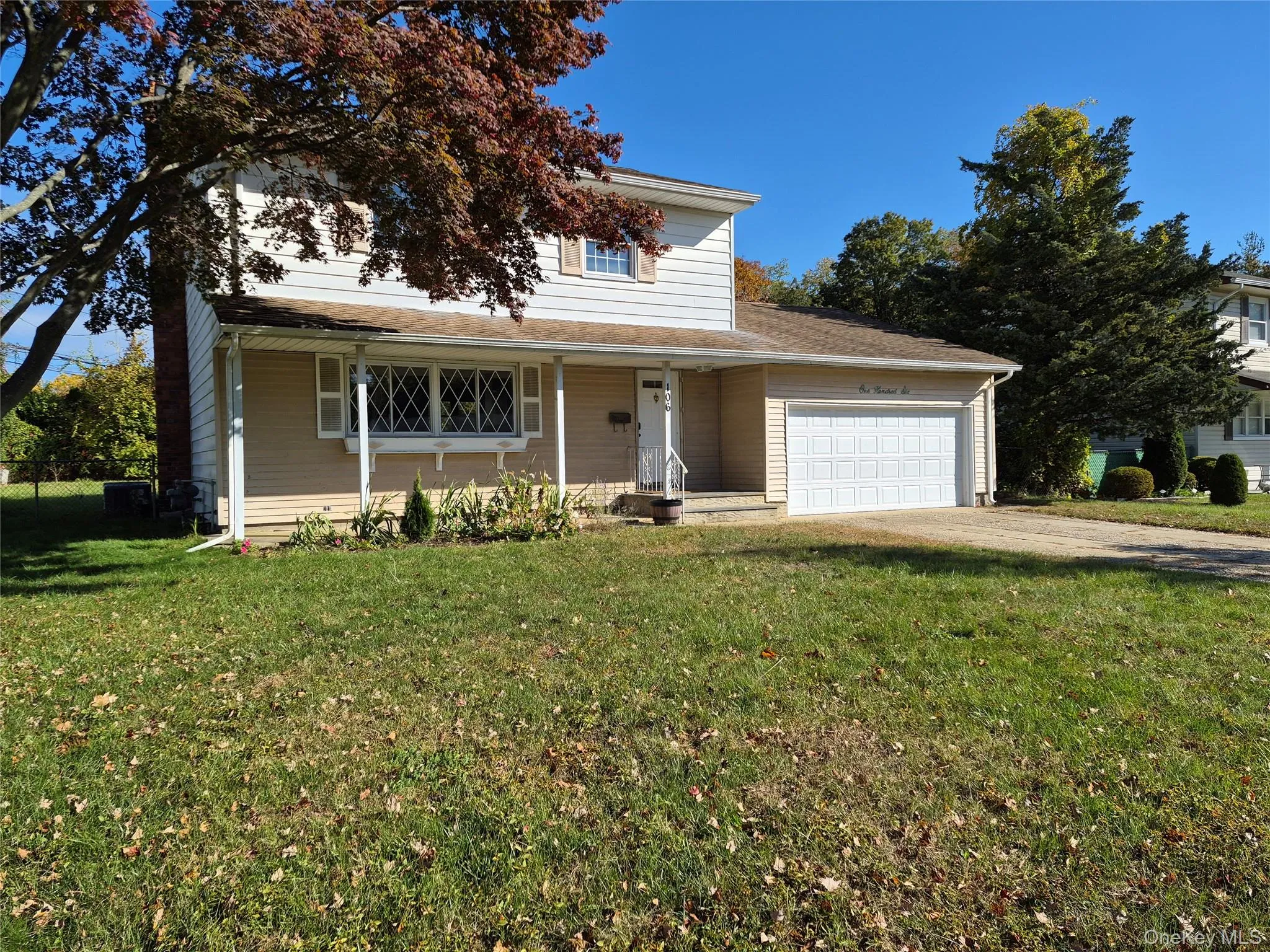Traditional-style house featuring covered porch, driveway, a front yard, and an attached garage Traditional-style house featuring covered porch, driveway, a front yard, and an attached garage