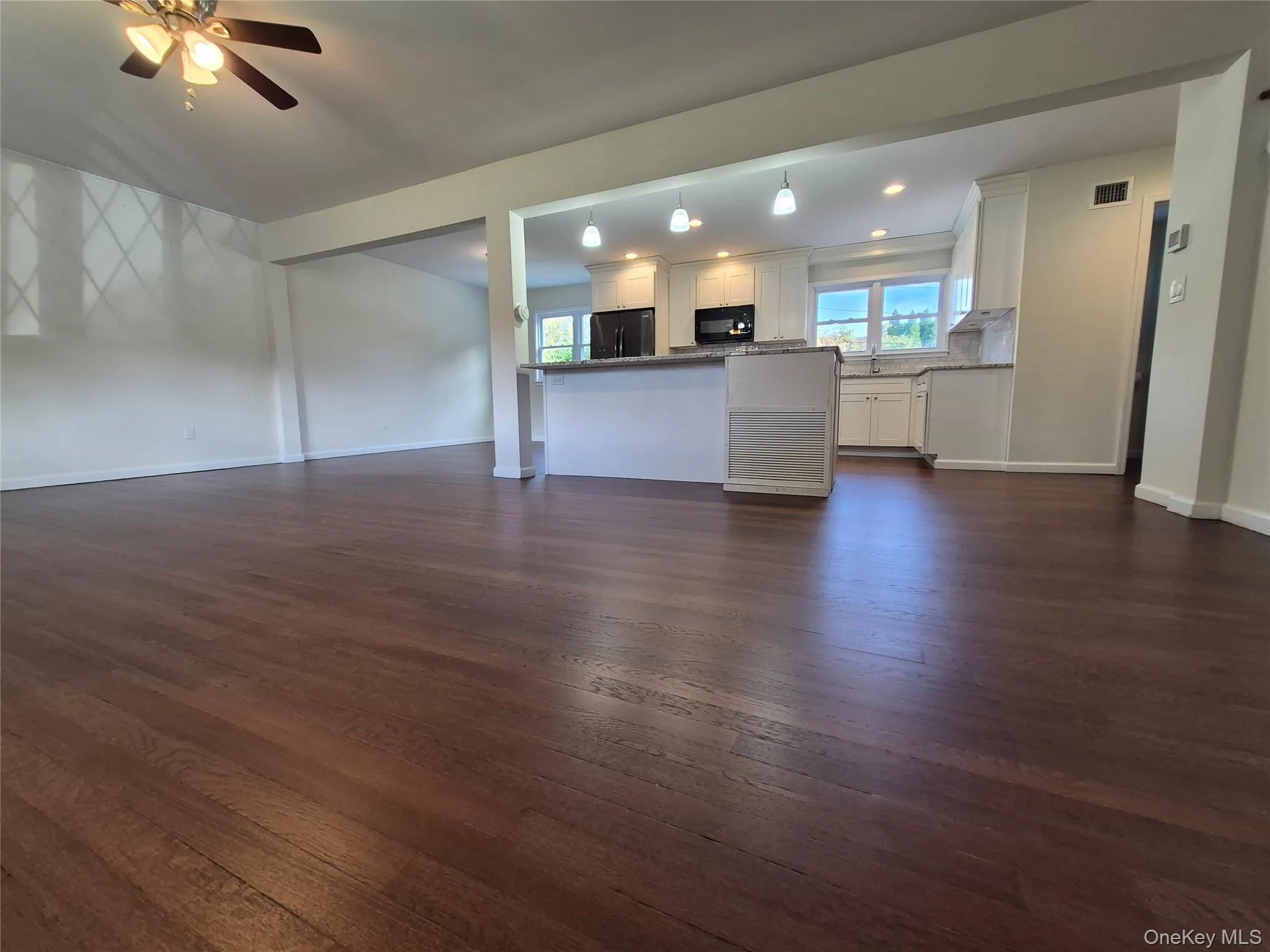 Unfurnished living room featuring dark wood-style flooring, ceiling fan, and recessed lighting Unfurnished living room featuring dark wood-style flooring, ceiling fan, and recessed lighting