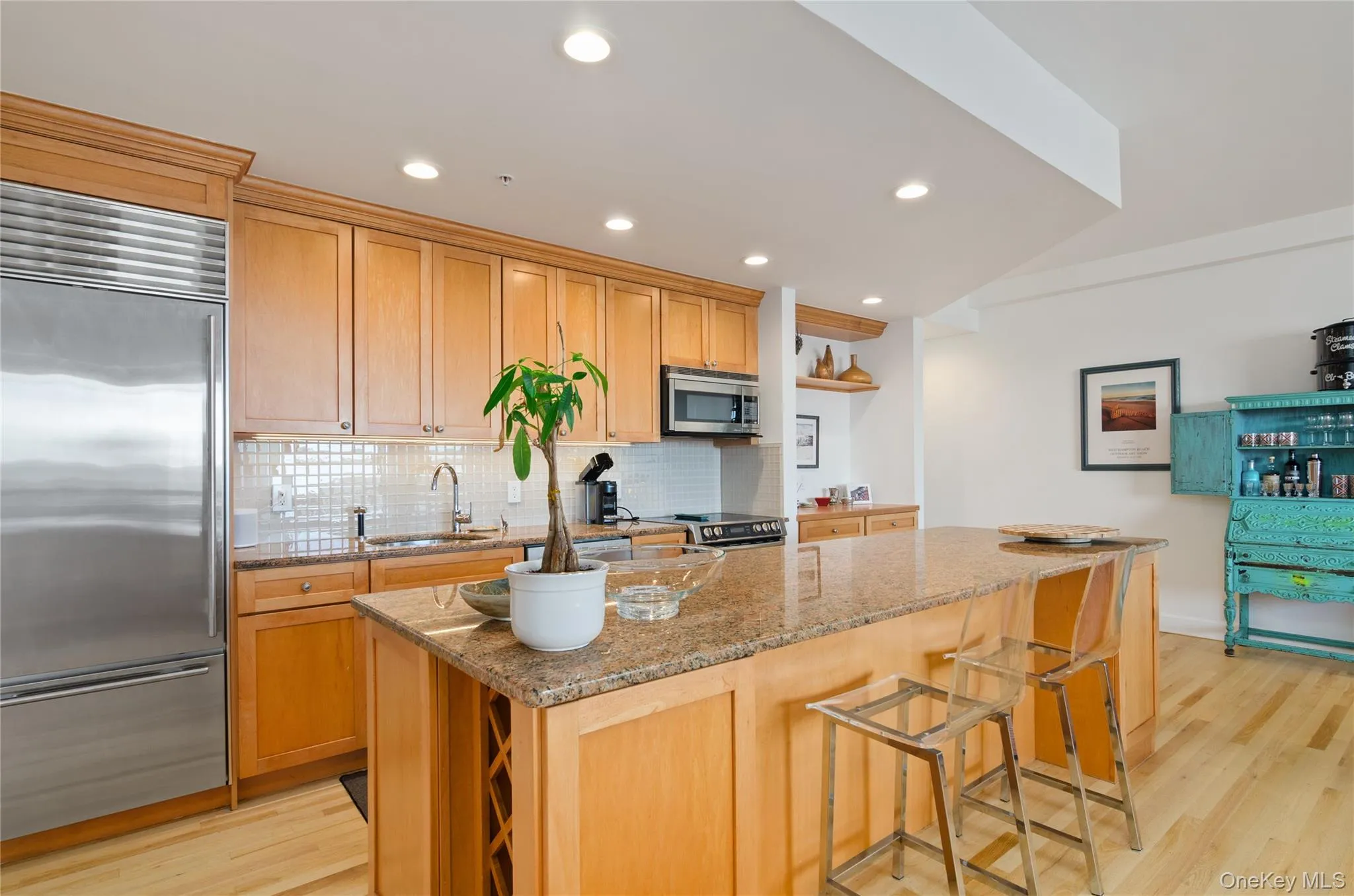 Kitchen with light stone counters, light wood-type flooring, stainless steel appliances, decorative backsplash, and recessed lighting Kitchen with light stone counters, light wood-type flooring, stainless steel appliances, decorative backsplash, and recessed lighting