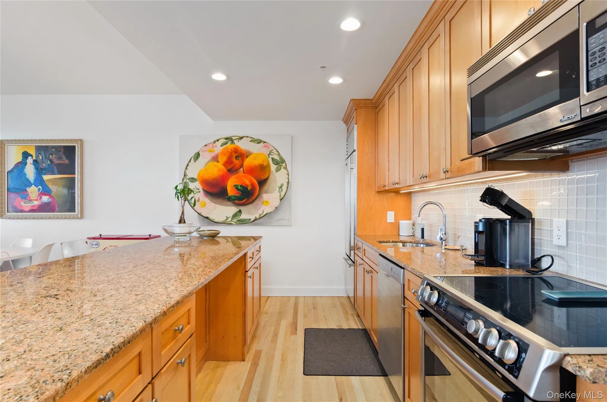 Kitchen featuring stainless steel appliances, light stone countertops, light wood-style flooring, recessed lighting, and decorative backsplash Kitchen featuring stainless steel appliances, light stone countertops, light wood-style flooring, recessed lighting, and decorative backsplash