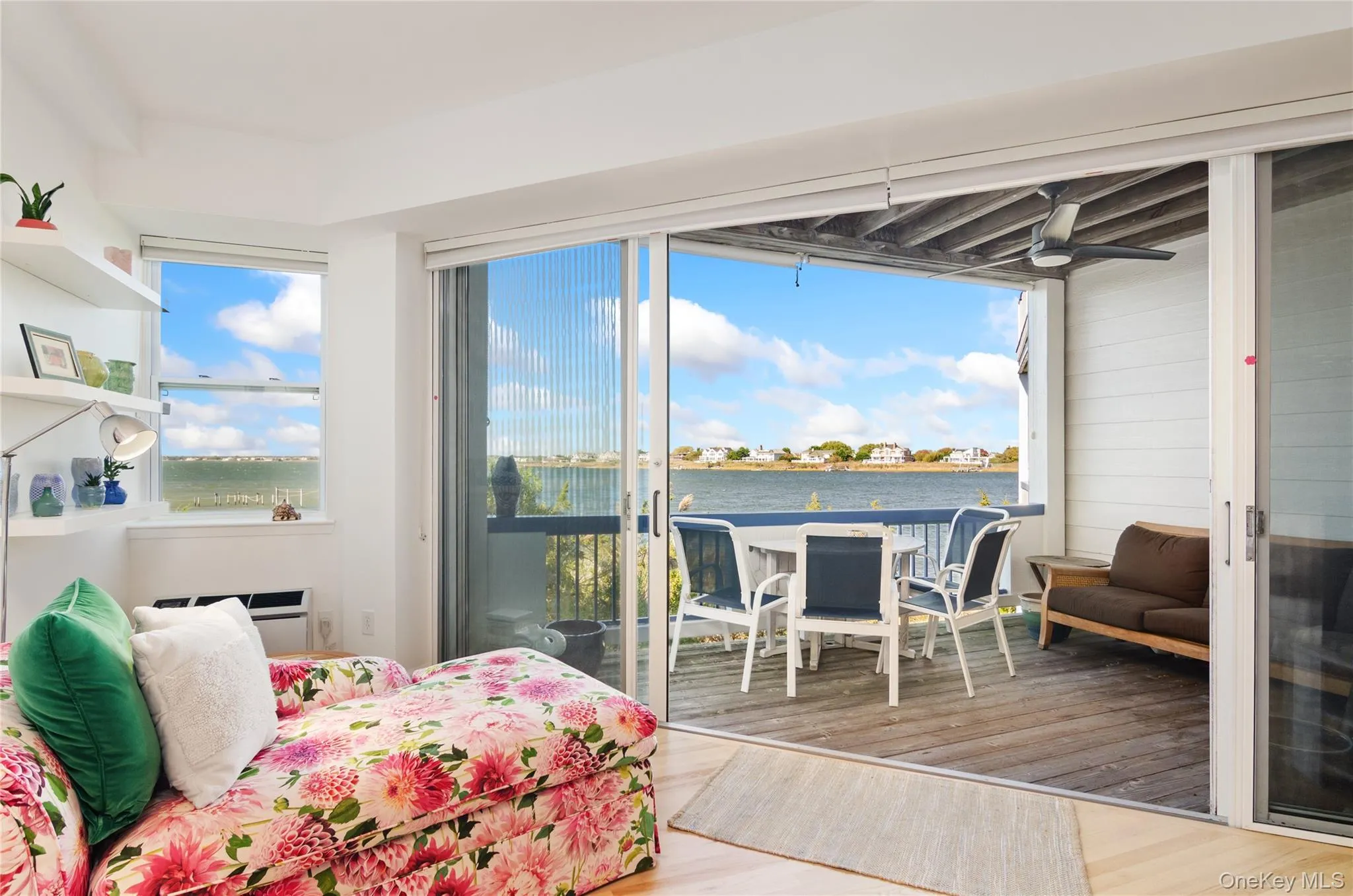Bedroom featuring wood finished floors, access to exterior, a water view, and a sunroom Bedroom featuring wood finished floors, access to exterior, a water view, and a sunroom