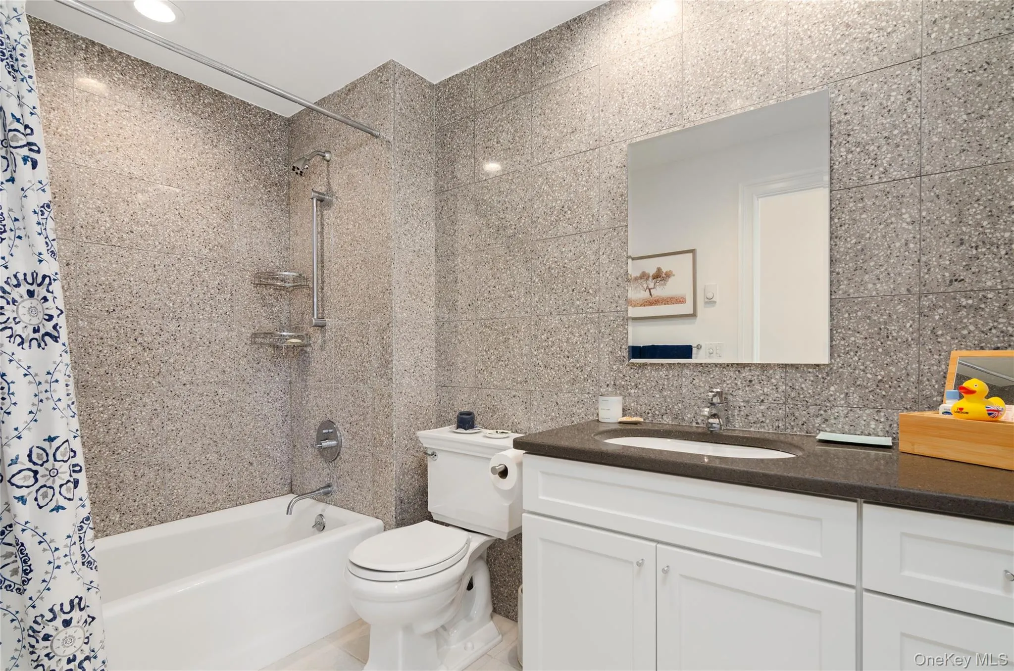 Bathroom featuring shower / bath combo with shower curtain, tile walls, and vanity Bathroom featuring shower / bath combo with shower curtain, tile walls, and vanity