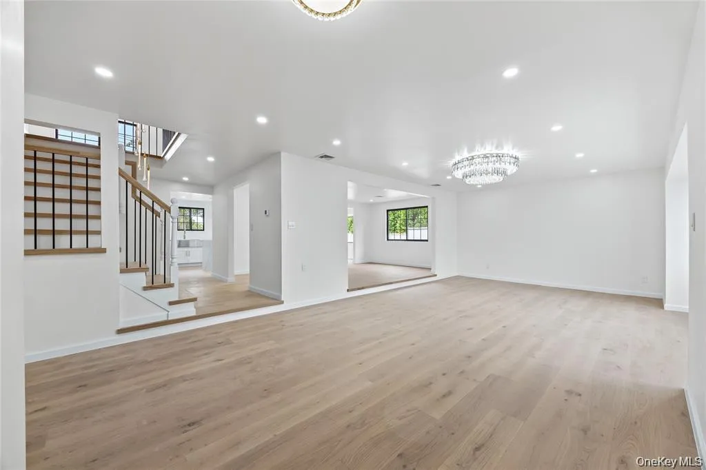 Unfurnished living room featuring light wood-style floors, recessed lighting, stairway, and a chandelier Unfurnished living room featuring light wood-style floors, recessed lighting, stairway, and a chandelier