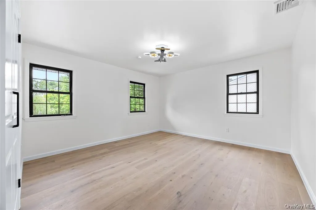 Empty room with healthy amount of natural light and light wood-style floors Empty room with healthy amount of natural light and light wood-style floors