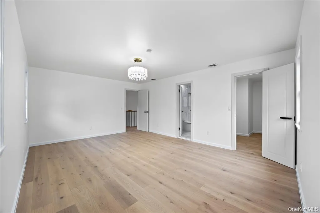 Unfurnished bedroom with a chandelier, light wood finished floors, and connected bathroom Unfurnished bedroom with a chandelier, light wood finished floors, and connected bathroom