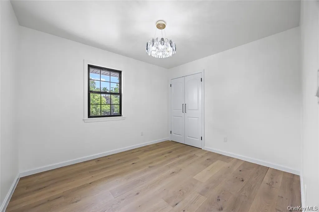 Empty room featuring light wood-type flooring and a chandelier Empty room featuring light wood-type flooring and a chandelier