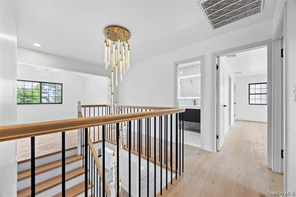 Hall with light wood-type flooring, a chandelier, and an upstairs landing Hall with light wood-type flooring, a chandelier, and an upstairs landing