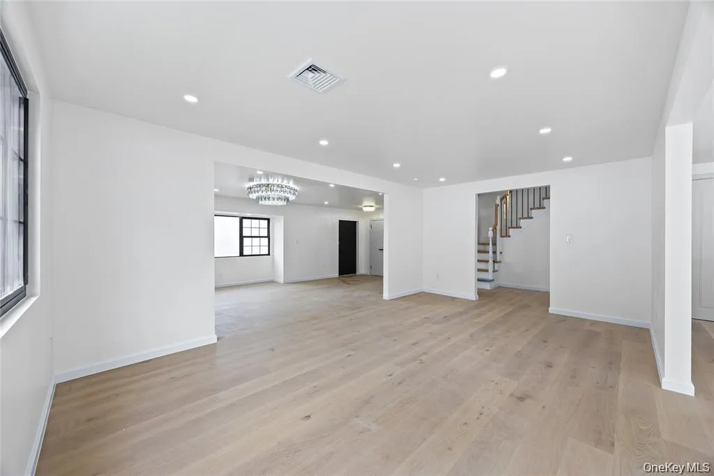 Unfurnished living room with light wood finished floors, recessed lighting, a chandelier, and stairway Unfurnished living room with light wood finished floors, recessed lighting, a chandelier, and stairway