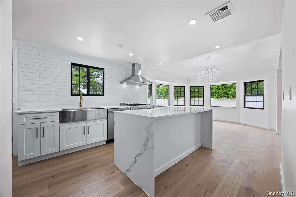 Kitchen with tasteful backsplash, recessed lighting, light wood-style floors, light stone countertops, and white cabinets Kitchen with tasteful backsplash, recessed lighting, light wood-style floors, light stone countertops, and white cabinets