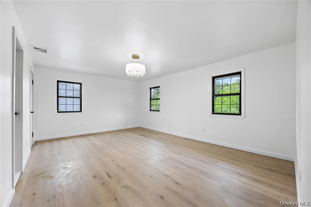 Unfurnished room with plenty of natural light, a chandelier, and light wood-style flooring Unfurnished room with plenty of natural light, a chandelier, and light wood-style flooring