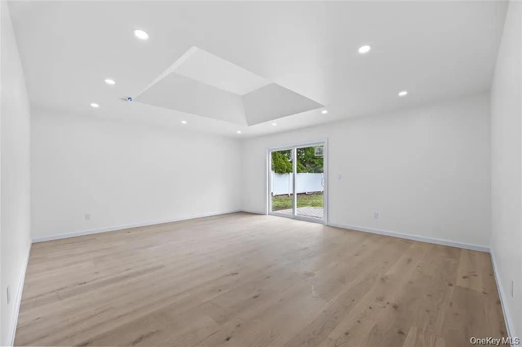 Unfurnished room with light wood finished floors, a tray ceiling, and recessed lighting Unfurnished room with light wood finished floors, a tray ceiling, and recessed lighting