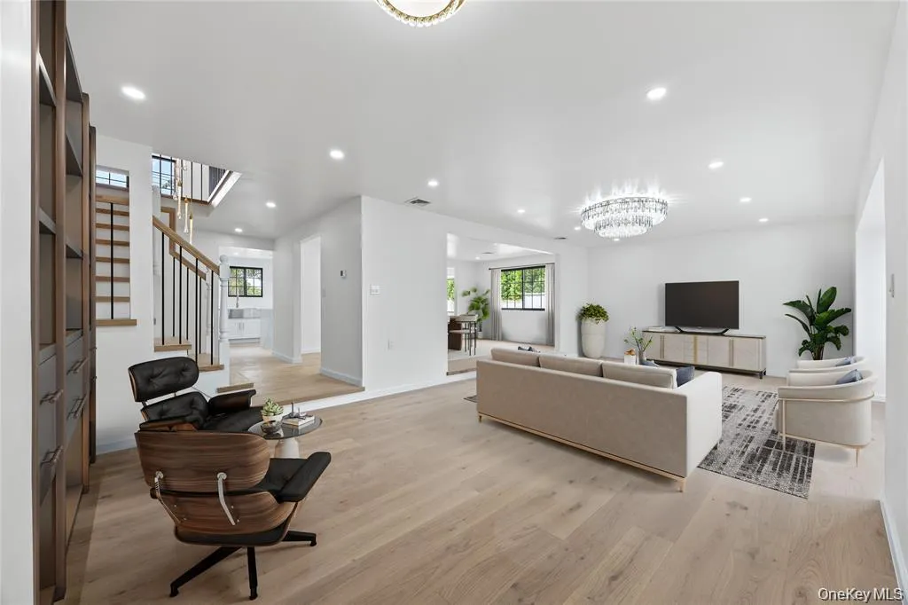 Living room featuring light wood-type flooring, recessed lighting, a chandelier, and stairs Living room featuring light wood-type flooring, recessed lighting, a chandelier, and stairs