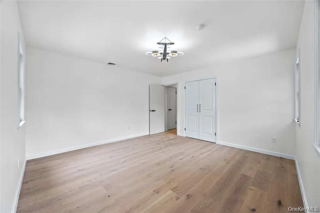 Unfurnished bedroom with light wood-type flooring, a closet, and a chandelier Unfurnished bedroom with light wood-type flooring, a closet, and a chandelier