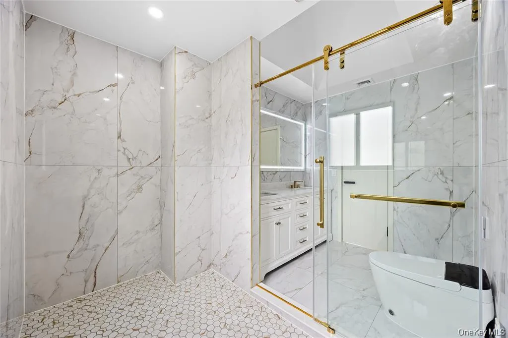 Bathroom with vanity, a marble finish shower, stone wall, tile walls, and light marble finish flooring Bathroom with vanity, a marble finish shower, stone wall, tile walls, and light marble finish flooring