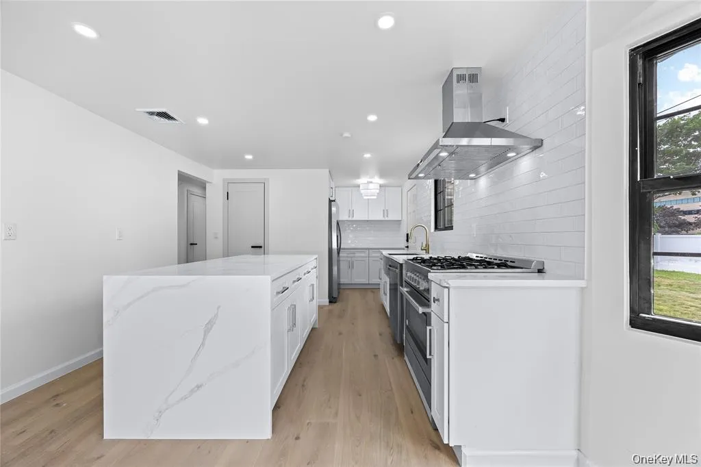 Kitchen featuring healthy amount of natural light, extractor fan, light stone countertops, appliances with stainless steel finishes, and recessed lighting Kitchen featuring healthy amount of natural light, extractor fan, light stone countertops, appliances with stainless steel finishes, and recessed lighting