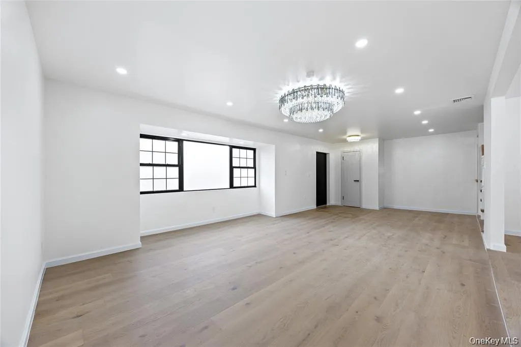 Unfurnished living room with recessed lighting, light wood-style floors, and a chandelier Unfurnished living room with recessed lighting, light wood-style floors, and a chandelier