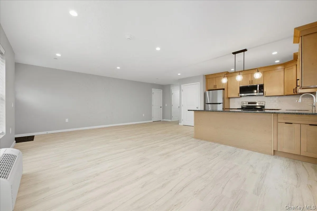 Living Room to Kitchen featuring open floor plan, decorative light fixtures, granite counters, luxury vinyl plank flooring, and recessed lighting Living Room to Kitchen featuring open floor plan, decorative light fixtures, granite counters, luxury vinyl plank flooring, and recessed lighting