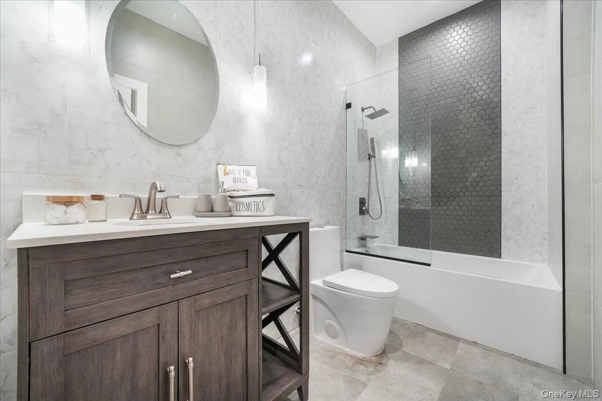 Bathroom featuring tile walls, shower / bathtub combination, and vanity Bathroom featuring tile walls, shower / bathtub combination, and vanity