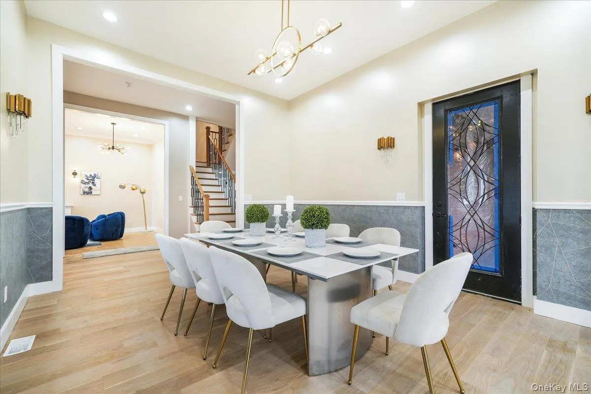 Dining room featuring a wainscoted wall, a chandelier, stairs, light wood-type flooring, and recessed lighting Dining room featuring a wainscoted wall, a chandelier, stairs, light wood-type flooring, and recessed lighting