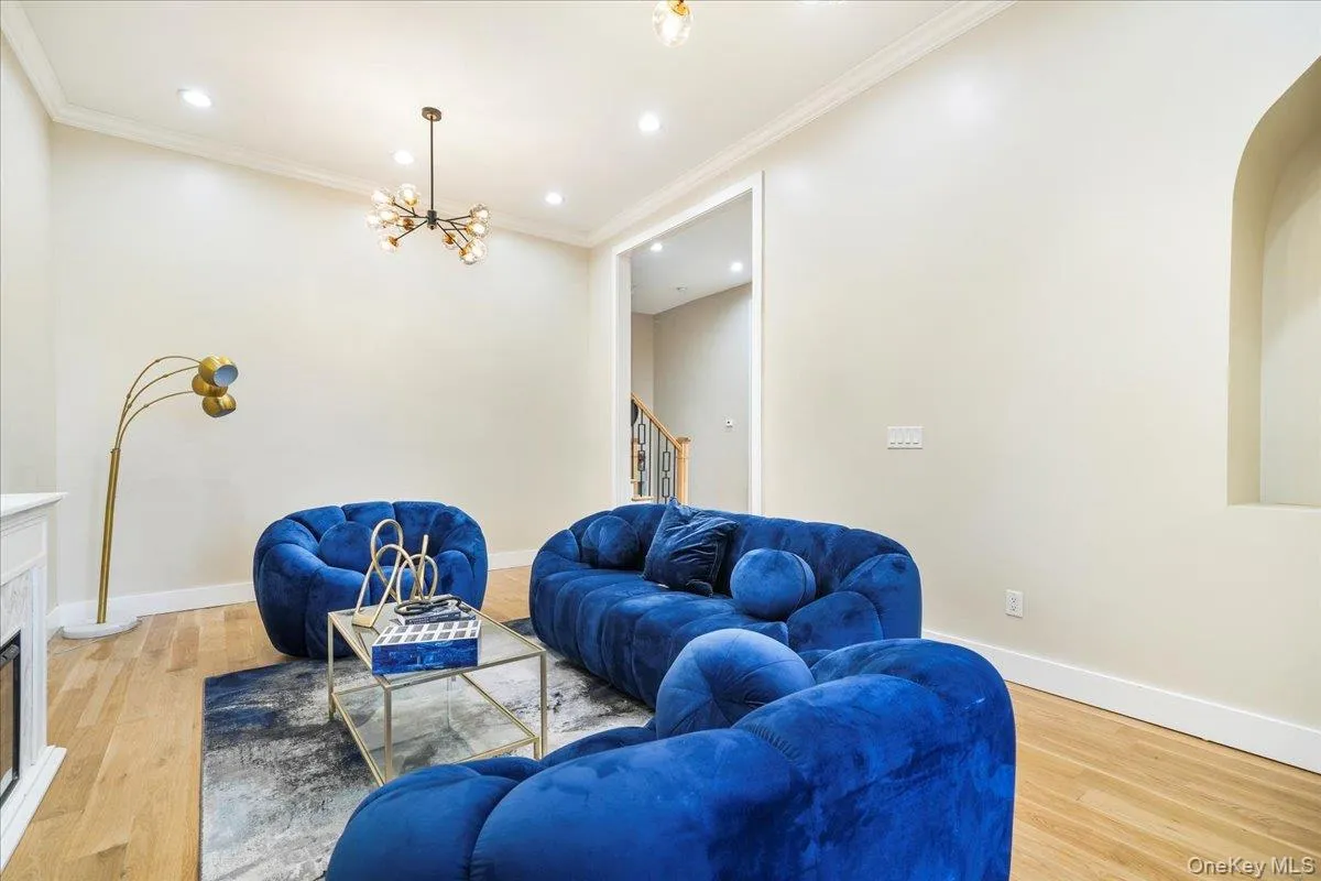 Living area featuring light wood-style flooring, ornamental molding, a fireplace, recessed lighting, and stairs Living area featuring light wood-style flooring, ornamental molding, a fireplace, recessed lighting, and stairs