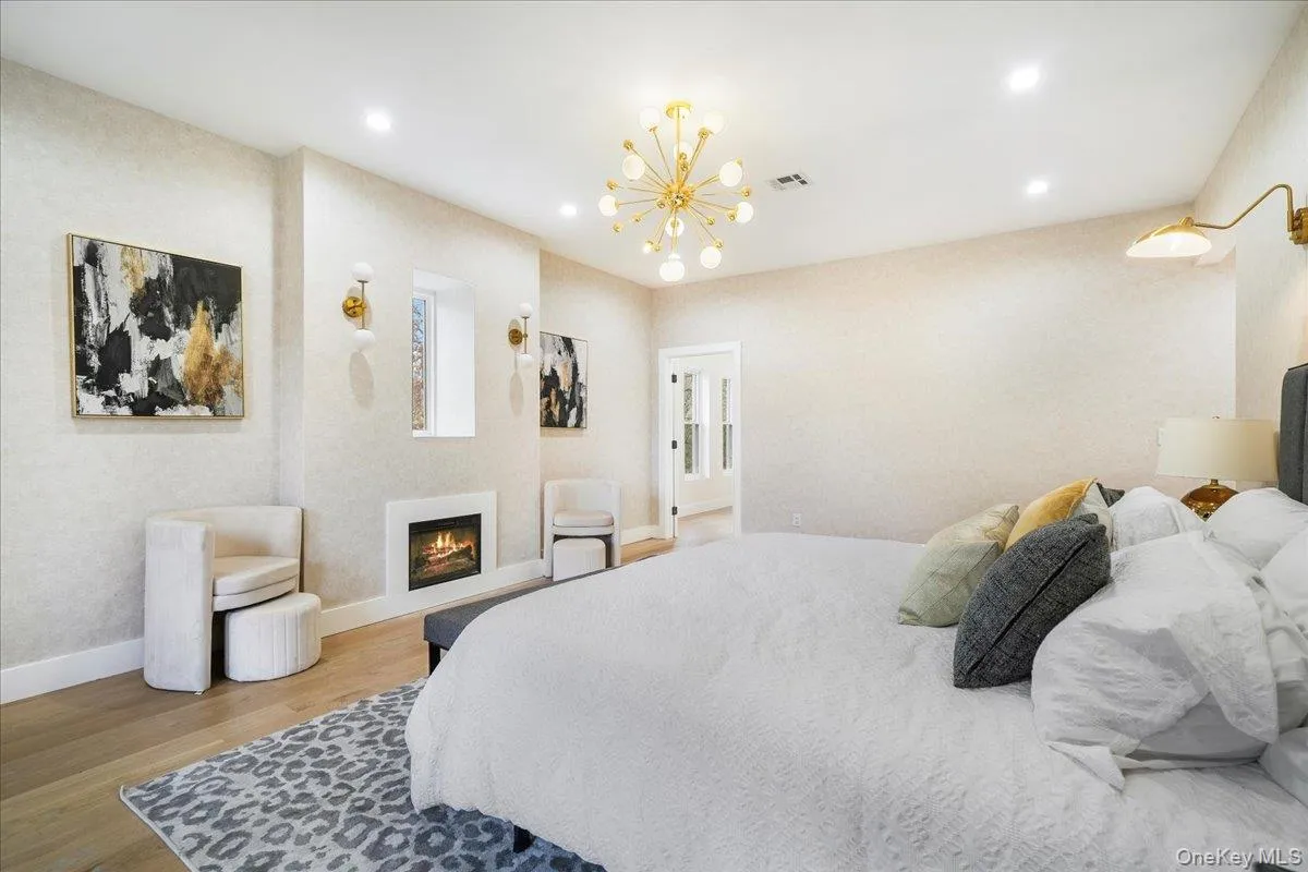 Bedroom featuring a lit fireplace, light wood finished floors, a chandelier, and recessed lighting Bedroom featuring a lit fireplace, light wood finished floors, a chandelier, and recessed lighting
