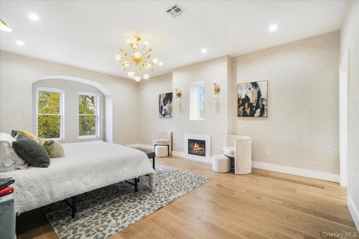 Bedroom with light wood-type flooring, a glass covered fireplace, recessed lighting, and a chandelier Bedroom with light wood-type flooring, a glass covered fireplace, recessed lighting, and a chandelier