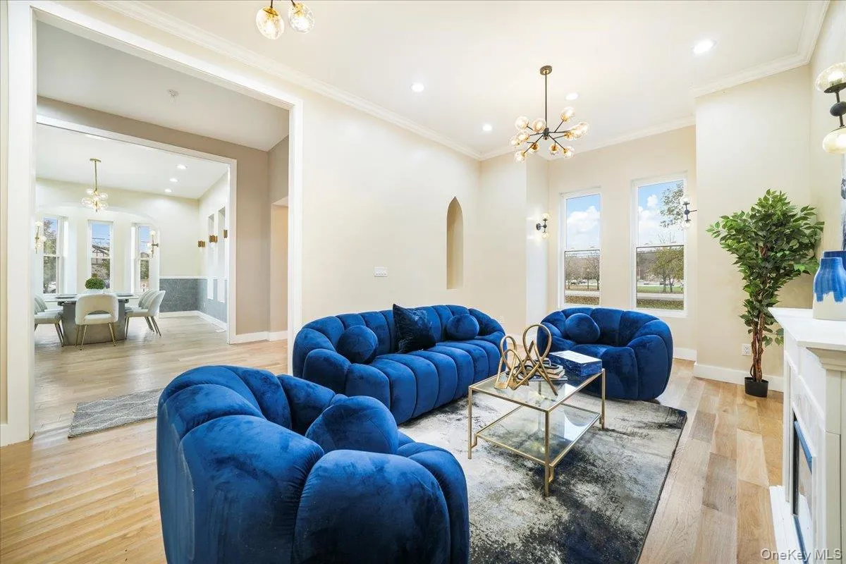 Living room with a chandelier, light wood-type flooring, recessed lighting, ornamental molding, and a fireplace Living room with a chandelier, light wood-type flooring, recessed lighting, ornamental molding, and a fireplace