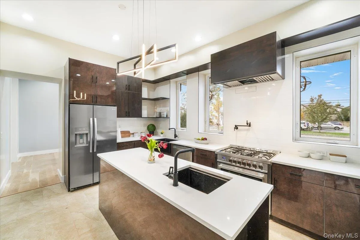 Kitchen with dark brown cabinets, stainless steel appliances, a kitchen island with sink, exhaust hood, and modern cabinets Kitchen with dark brown cabinets, stainless steel appliances, a kitchen island with sink, exhaust hood, and modern cabinets