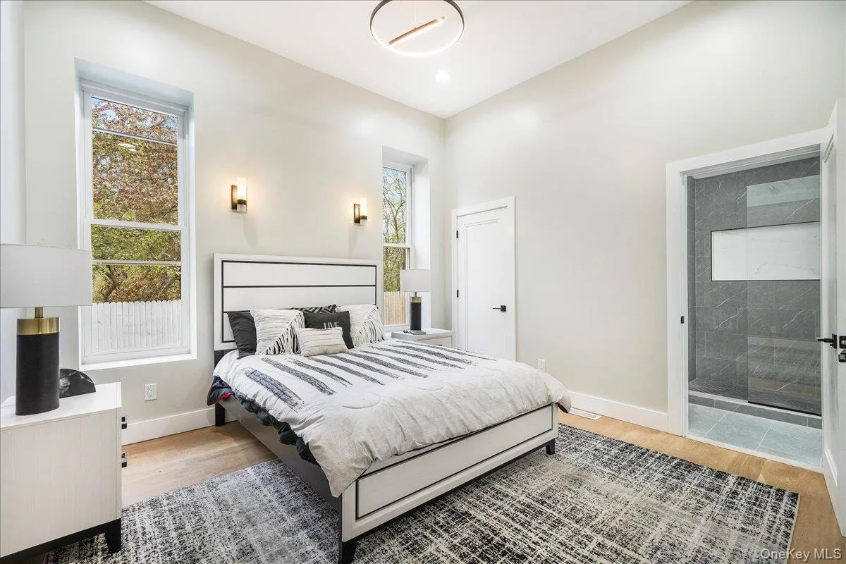 Bedroom featuring light wood finished floors and ensuite bath Bedroom featuring light wood finished floors and ensuite bath