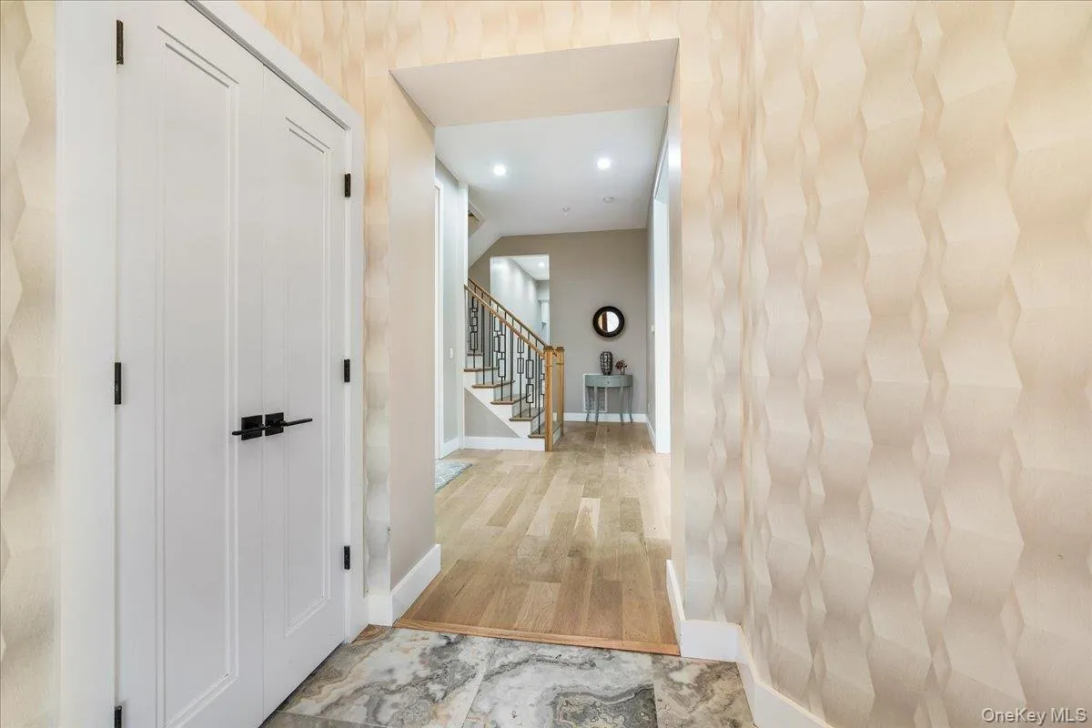 Hallway with stairway, light wood-style flooring, and recessed lighting Hallway with stairway, light wood-style flooring, and recessed lighting