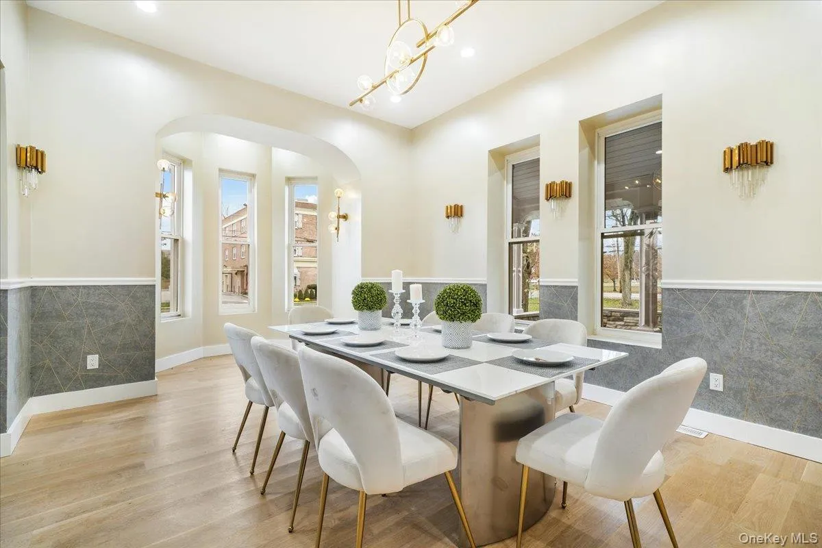 Dining room featuring arched walkways, light wood-style flooring, a wainscoted wall, recessed lighting, and a chandelier Dining room featuring arched walkways, light wood-style flooring, a wainscoted wall, recessed lighting, and a chandelier