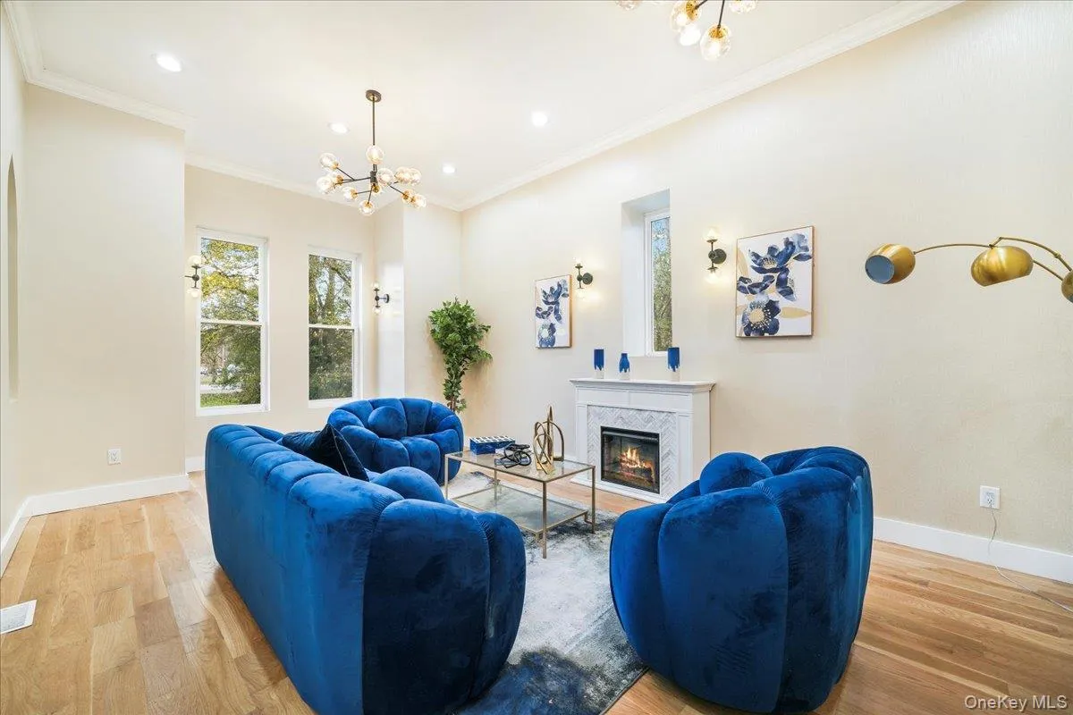 Living area featuring a chandelier, crown molding, light wood-style floors, a premium fireplace, and recessed lighting Living area featuring a chandelier, crown molding, light wood-style floors, a premium fireplace, and recessed lighting