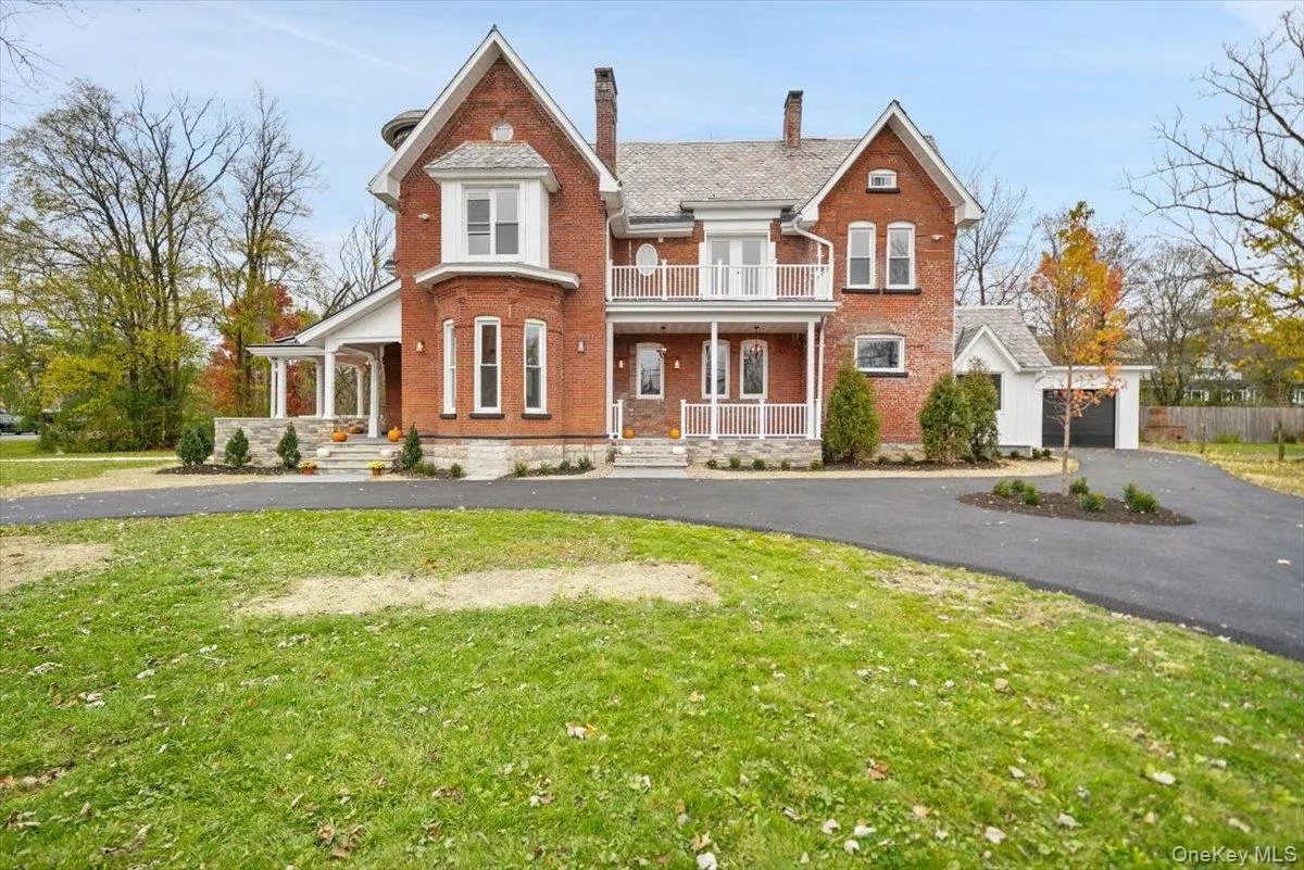 View of front facade with brick siding, a front lawn, a chimney, a balcony, and a porch View of front facade with brick siding, a front lawn, a chimney, a balcony, and a porch