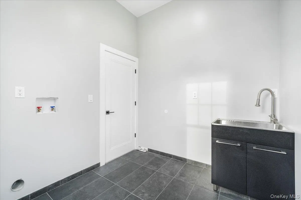 Laundry room with dark tile patterned flooring and washer hookup Laundry room with dark tile patterned flooring and washer hookup