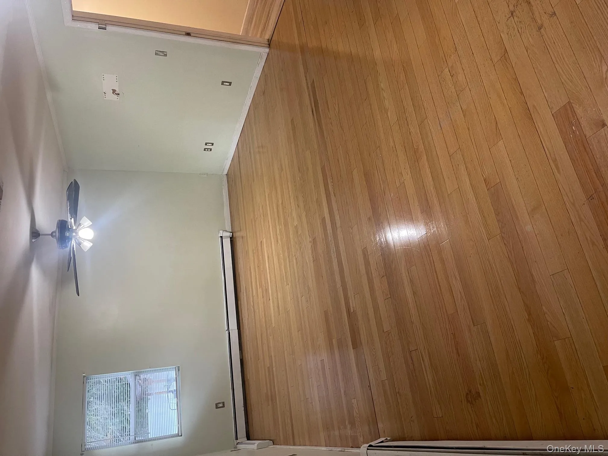 Empty room with light wood-style flooring, a baseboard heating unit, and a ceiling fan Empty room with light wood-style flooring, a baseboard heating unit, and a ceiling fan