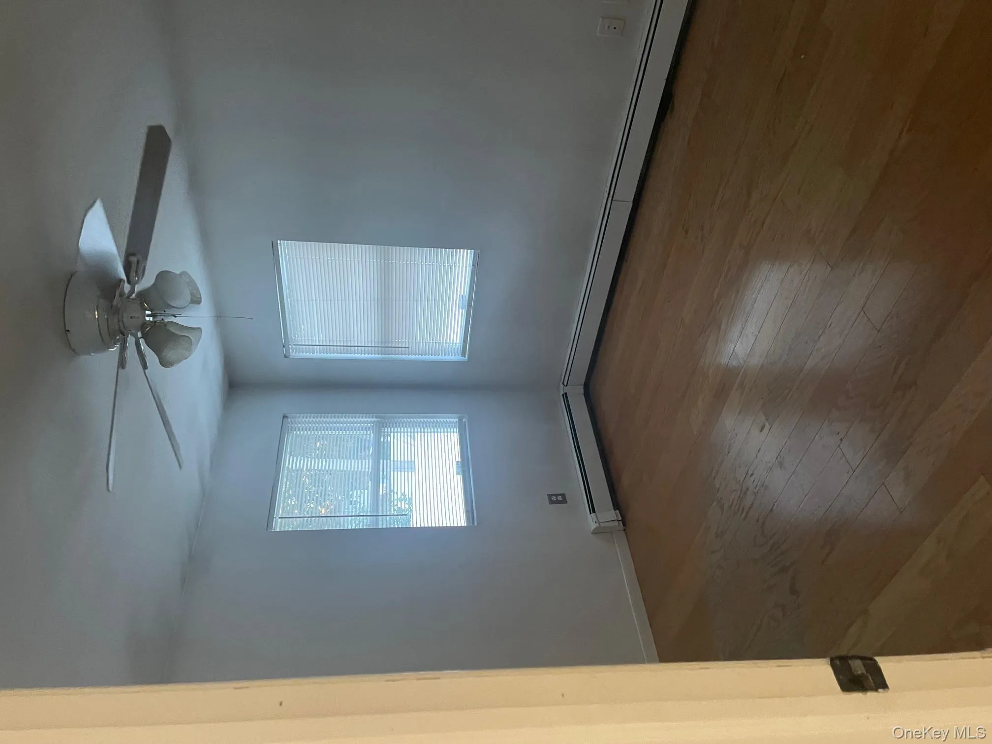 Empty room featuring wood-type flooring, a baseboard radiator, and a ceiling fan Empty room featuring wood-type flooring, a baseboard radiator, and a ceiling fan