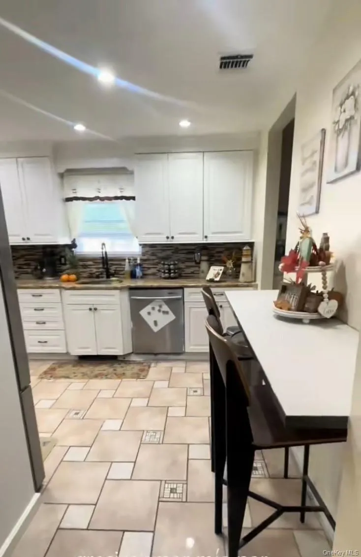 Kitchen featuring white cabinets, tasteful backsplash, stainless steel appliances, light countertops, and recessed lighting Kitchen featuring white cabinets, tasteful backsplash, stainless steel appliances, light countertops, and recessed lighting