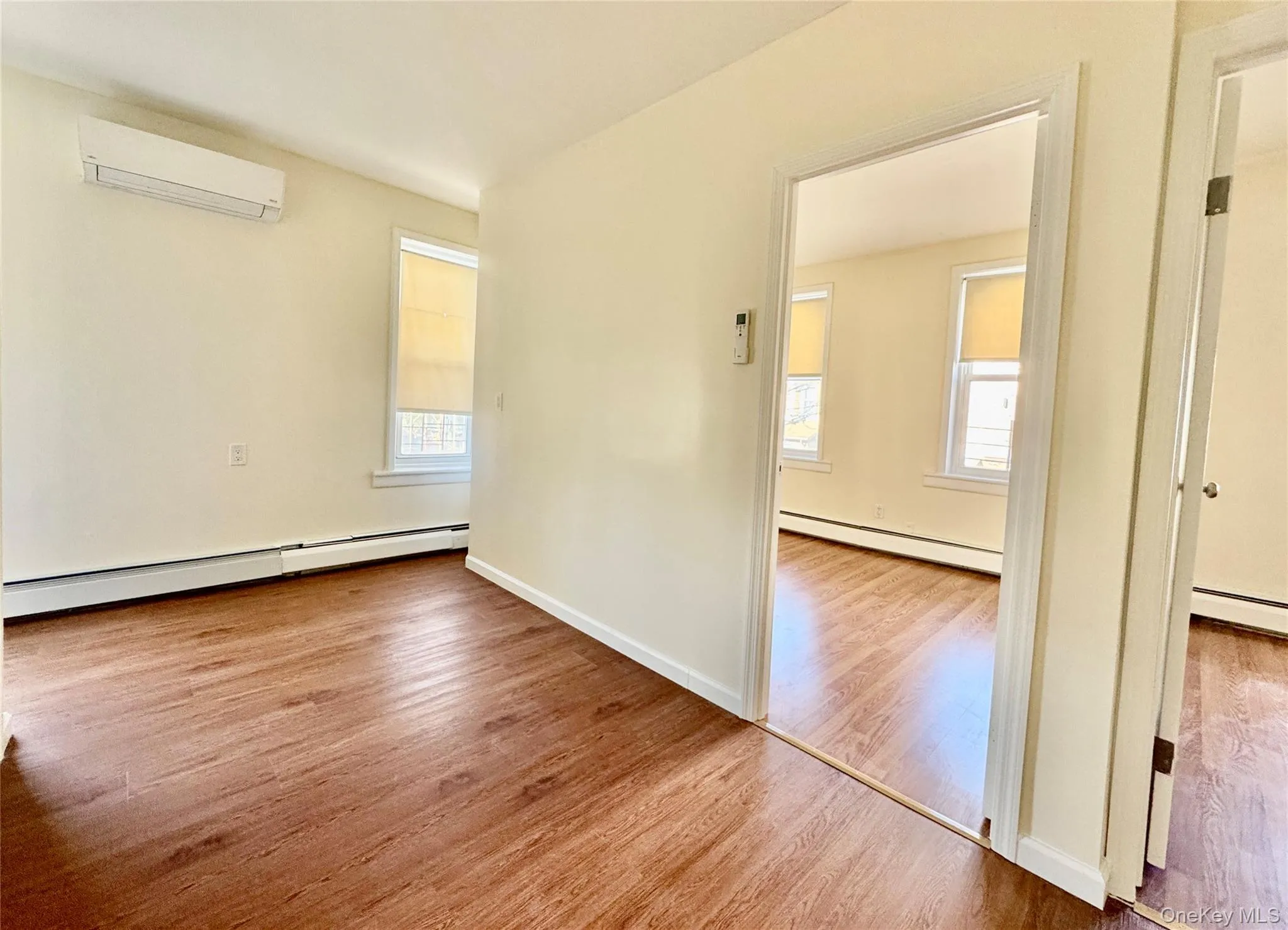 Spare room featuring wood finished floors, a baseboard radiator, and healthy amount of natural light Spare room featuring wood finished floors, a baseboard radiator, and healthy amount of natural light