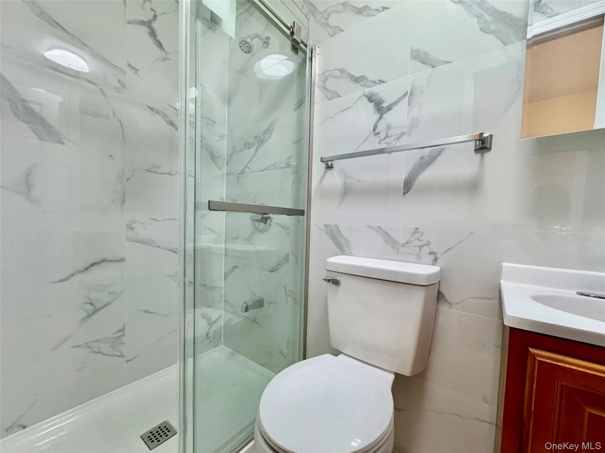 Full bath featuring vanity, a marble finish shower, and tile walls Full bath featuring vanity, a marble finish shower, and tile walls