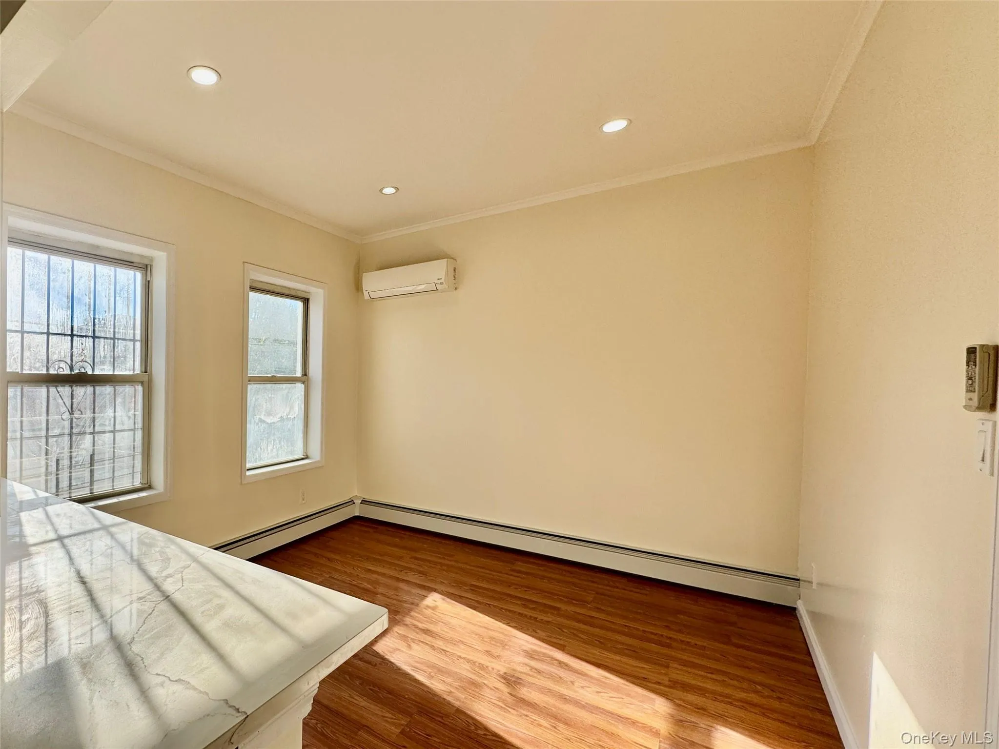 Unfurnished bedroom featuring dark wood finished floors, ornamental molding, a baseboard radiator, recessed lighting, and an AC wall unit Unfurnished bedroom featuring dark wood finished floors, ornamental molding, a baseboard radiator, recessed lighting, and an AC wall unit