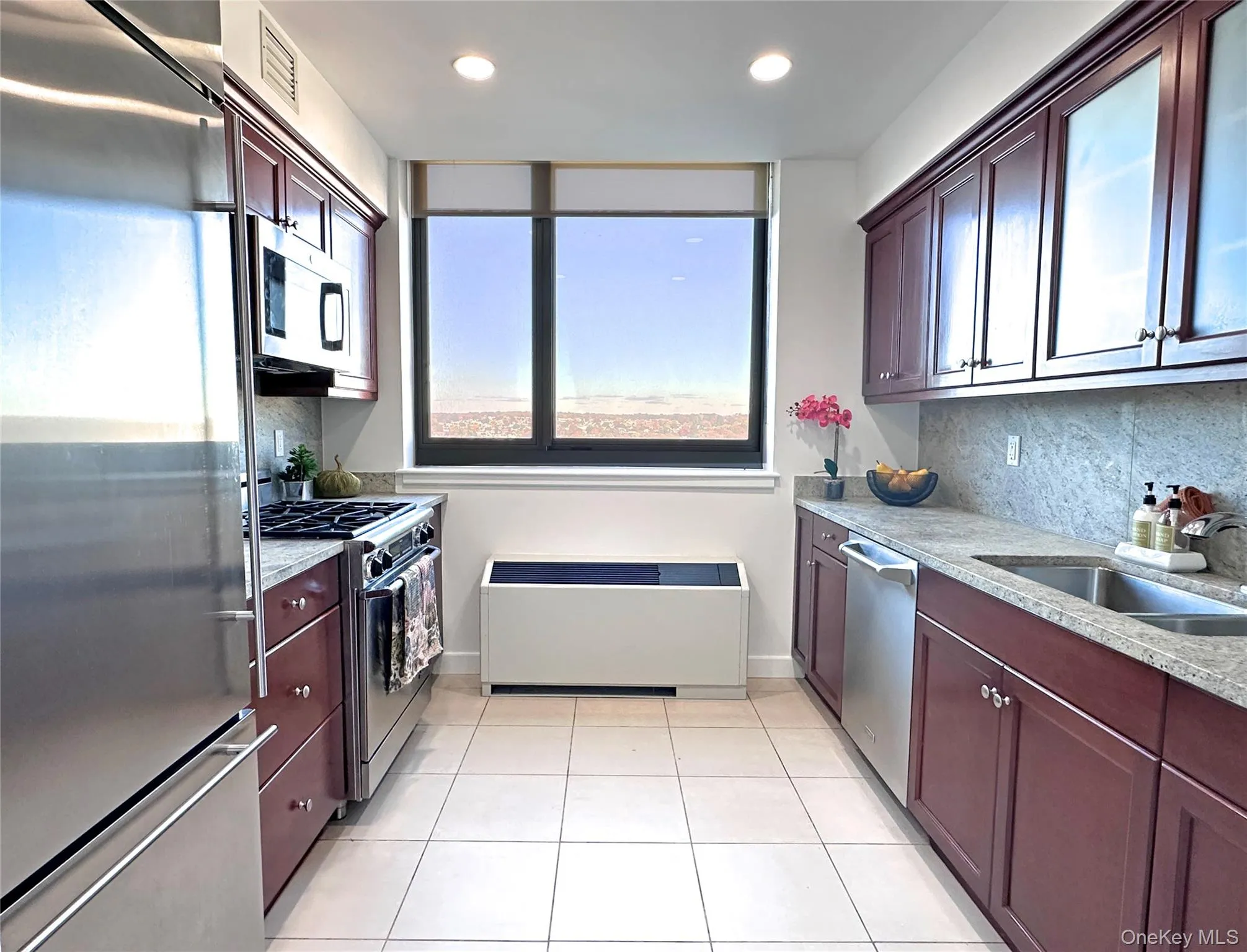 Kitchen with appliances with stainless steel finishes, granite counters, light tile patterned flooring, radiator, and decorative backsplash Kitchen with appliances with stainless steel finishes, granite counters, light tile patterned flooring, radiator, and decorative backsplash