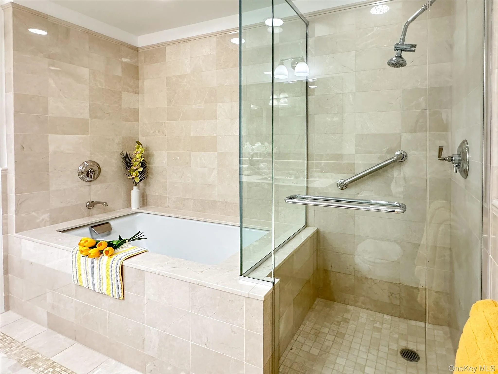 Primary bathroom featuring tile walls, a walk-in shower, light tile patterned floors, and spa-like tub. Primary bathroom featuring tile walls, a walk-in shower, light tile patterned floors, and spa-like tub.