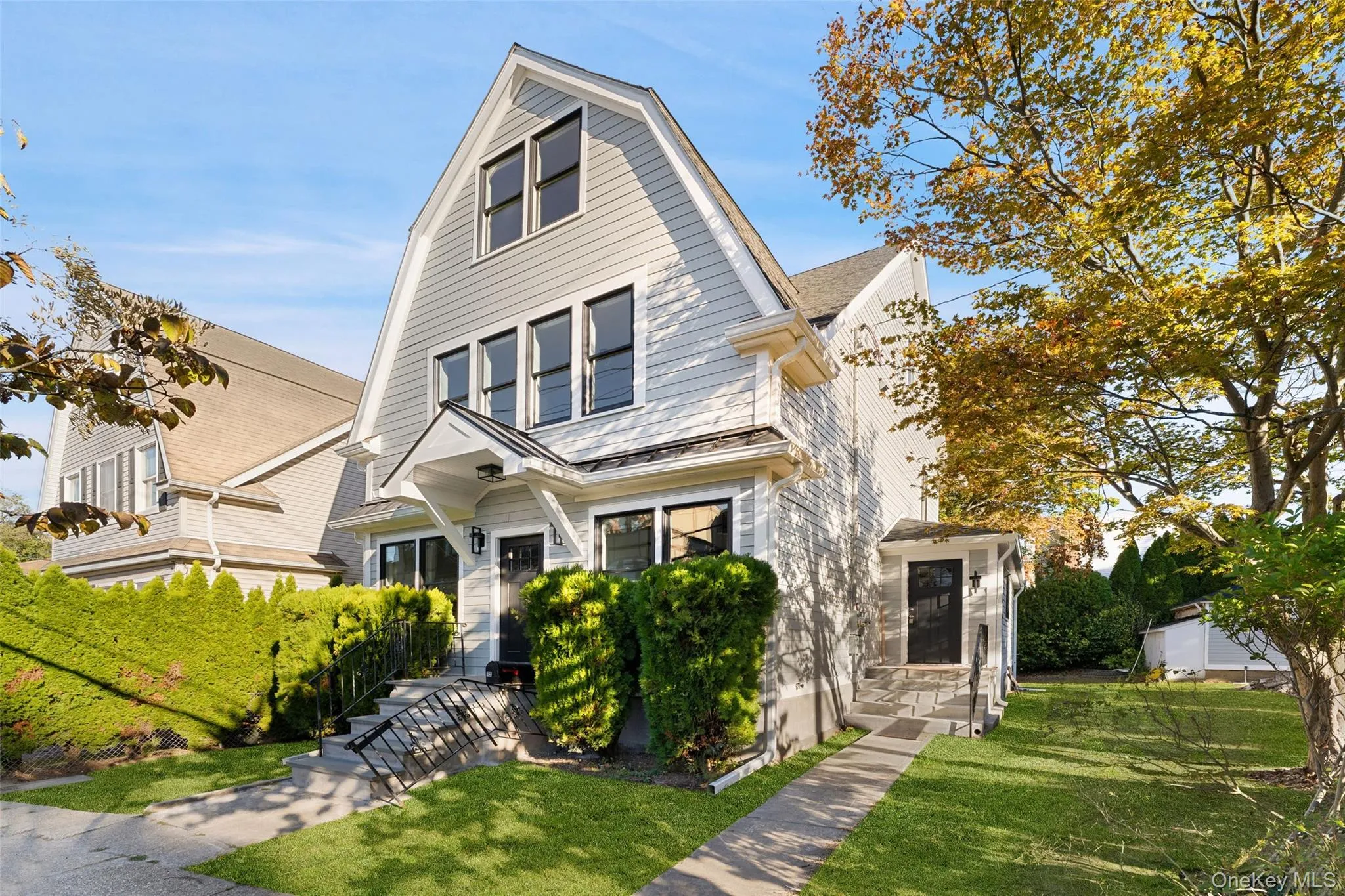 Colonial inspired home featuring a gambrel roof and a front yard Colonial inspired home featuring a gambrel roof and a front yard