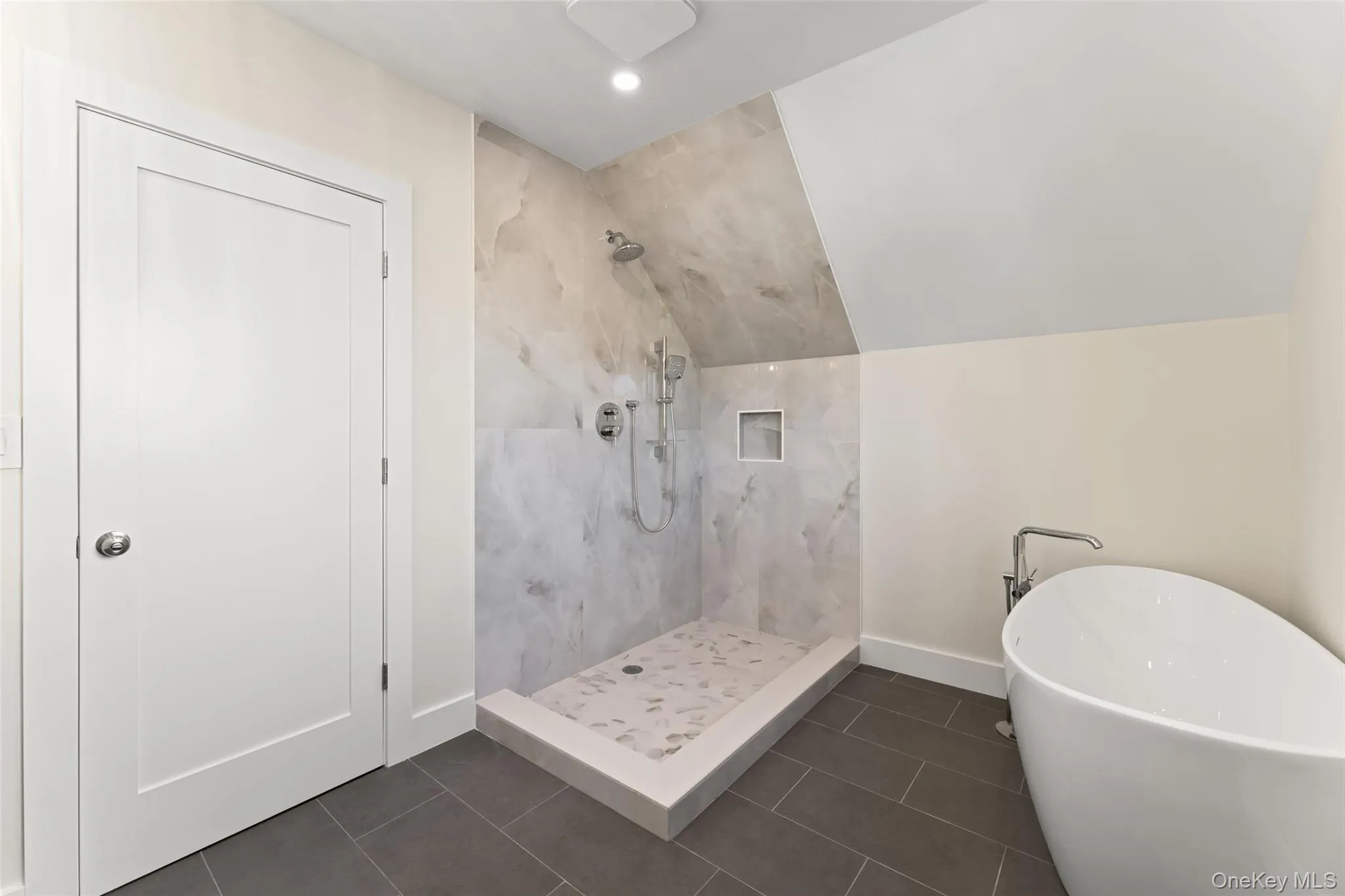 Full bath with dark tile patterned flooring, a marble finish shower, a freestanding tub, and vaulted ceiling Full bath with dark tile patterned flooring, a marble finish shower, a freestanding tub, and vaulted ceiling