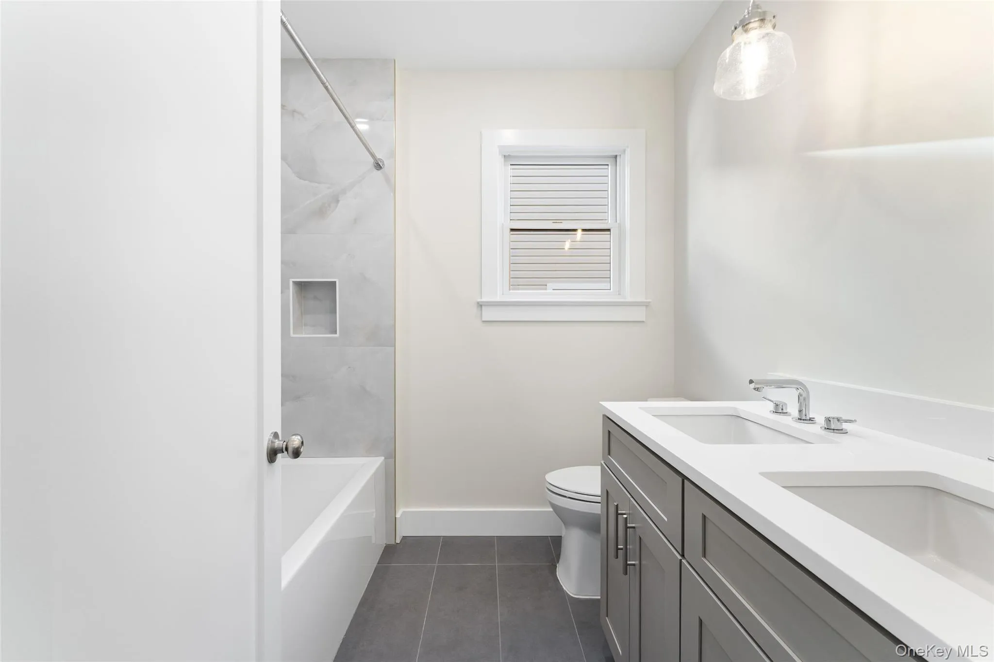 Full bath featuring double vanity, dark tile patterned floors, and shower / bathtub combination Full bath featuring double vanity, dark tile patterned floors, and shower / bathtub combination
