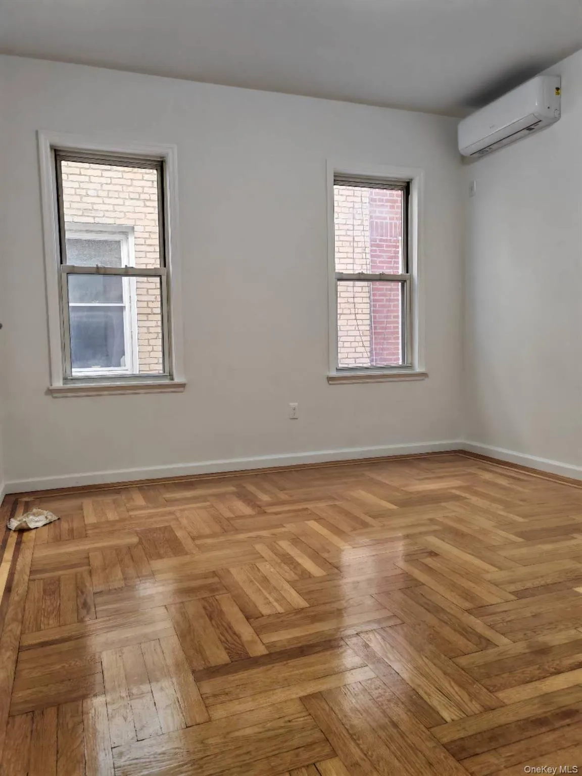 Empty room with an AC wall unit and baseboards Empty room with an AC wall unit and baseboards