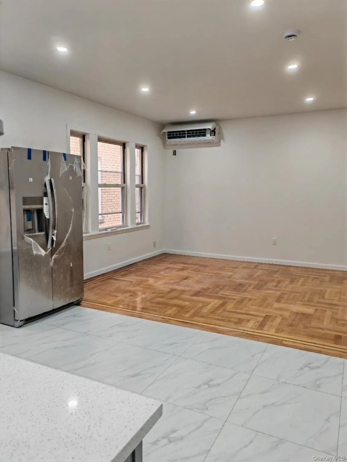Kitchen featuring stainless steel fridge, recessed lighting, and a wall unit AC Kitchen featuring stainless steel fridge, recessed lighting, and a wall unit AC