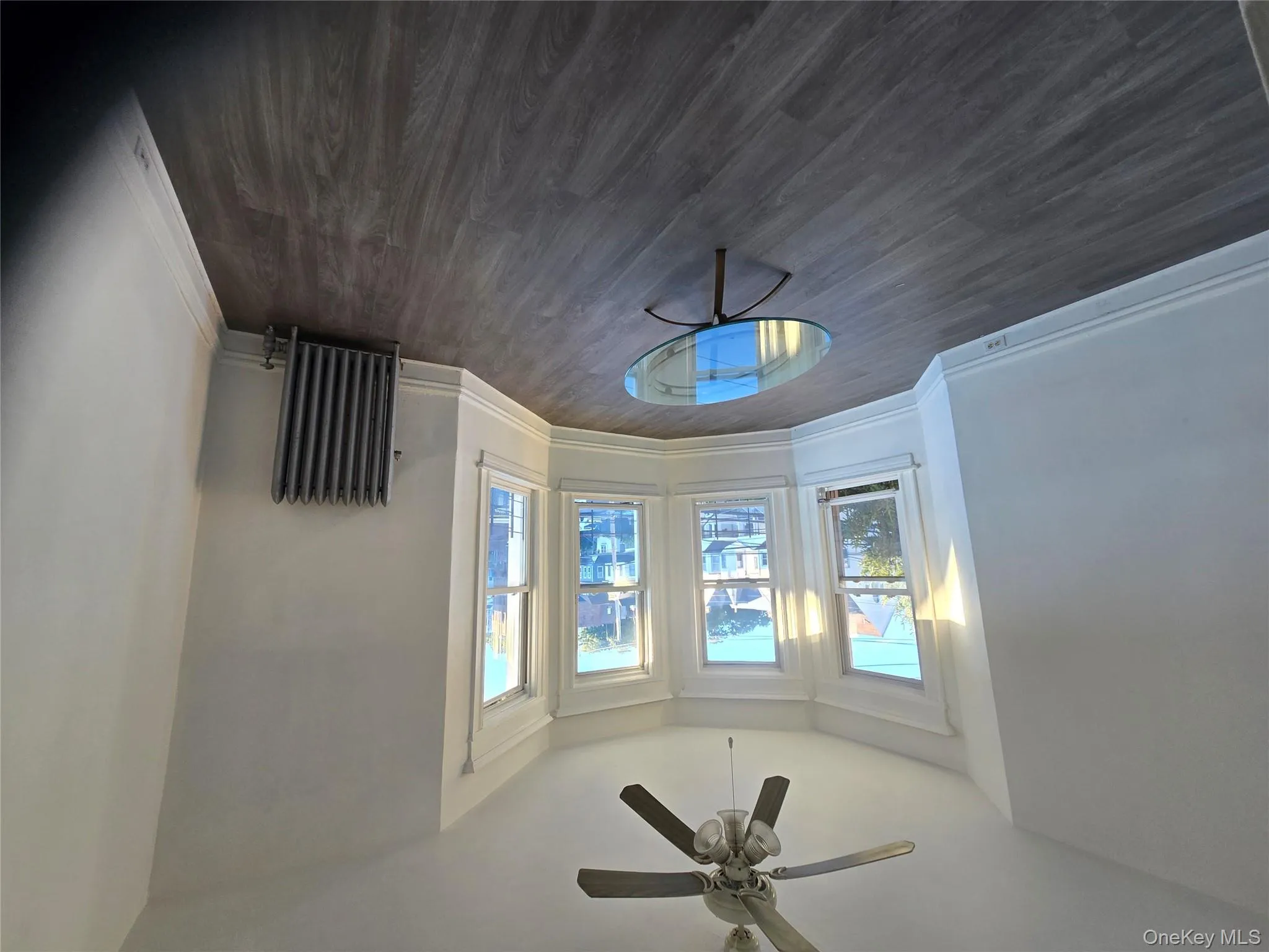 Unfurnished living room featuring radiator, dark wood-style floors, and ceiling fan Unfurnished living room featuring radiator, dark wood-style floors, and ceiling fan