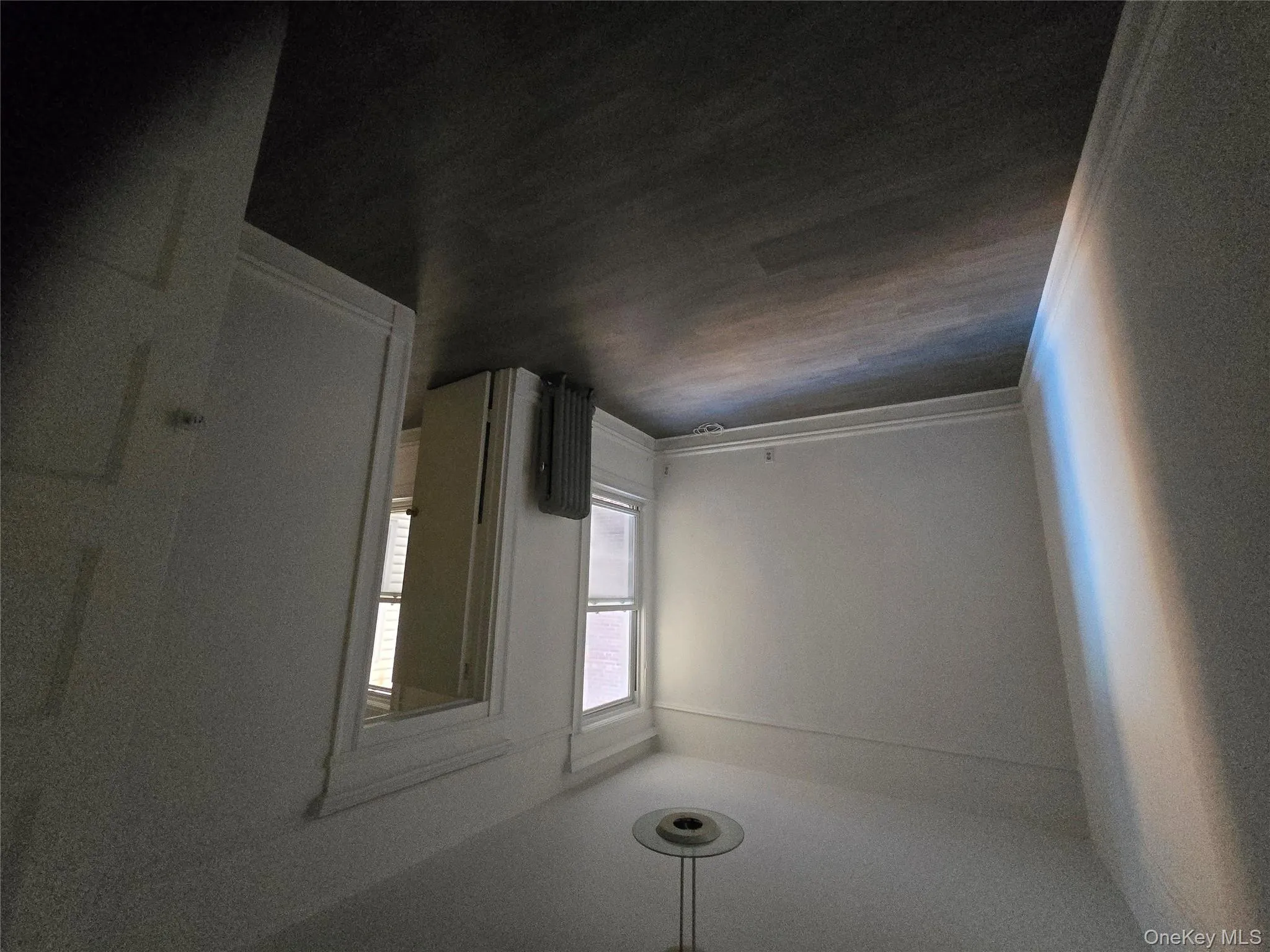 Spare room featuring dark wood-style floors and radiator heating unit Spare room featuring dark wood-style floors and radiator heating unit